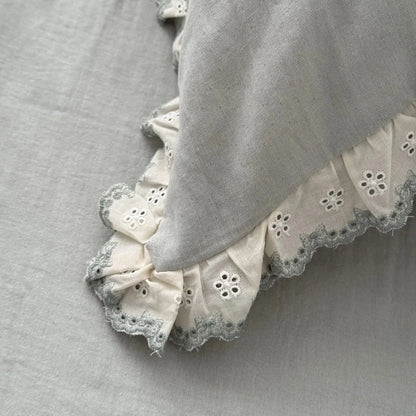 Detailed close-up of the embroidered lace ruffle trim on the sage green pillowcase, showing the fabric's texture.
