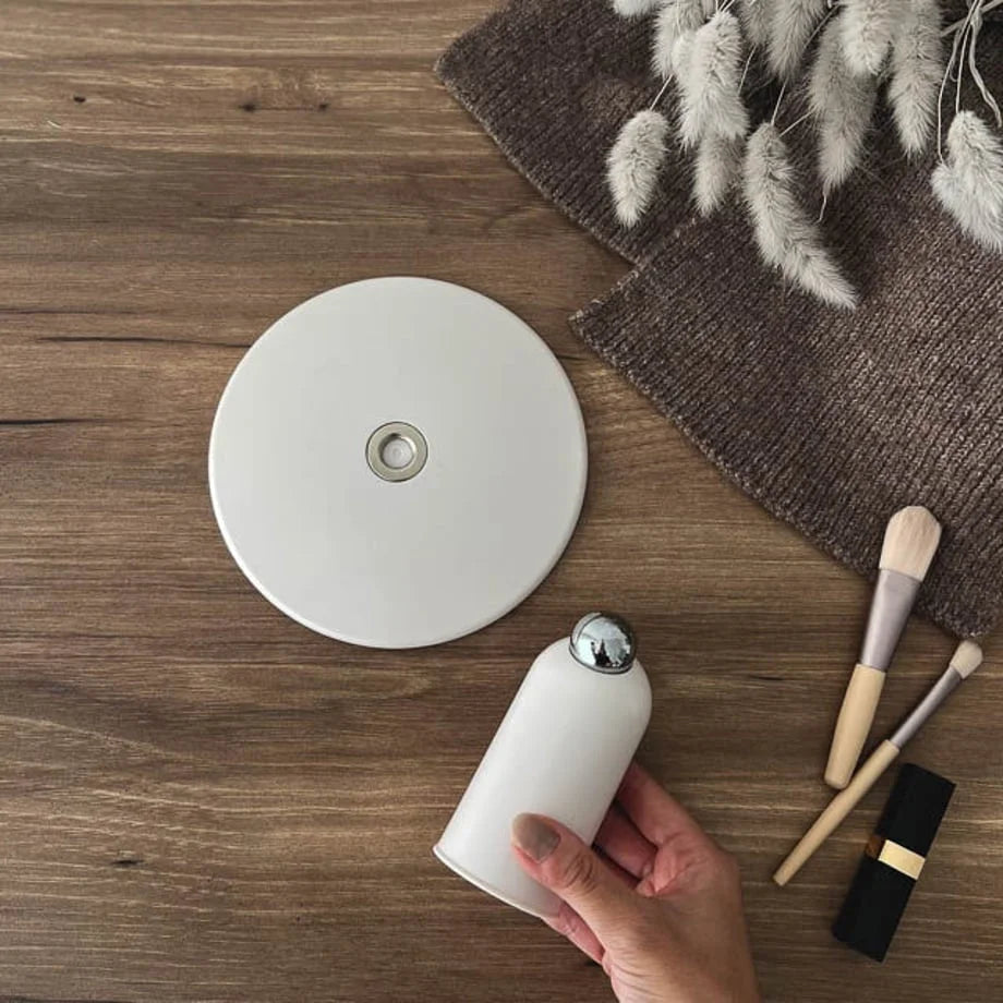 A hand holding the base of the white mirror to show its size and magnetic joint.