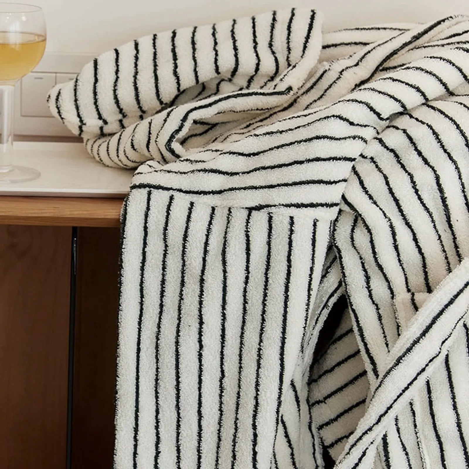 Folded striped robe placed on a table next to a glass of wine, evoking a relaxing spa evening atmosphere.