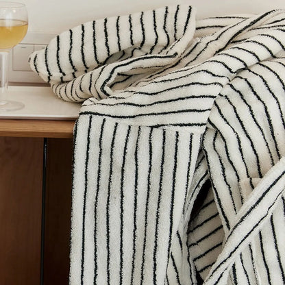 Folded striped robe placed on a table next to a glass of wine, evoking a relaxing spa evening atmosphere.