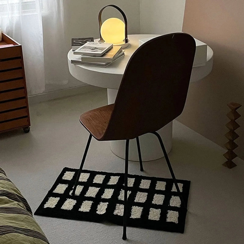 Tufted block grid rug placed under a modern wooden chair in a raw-floored room - RoomDen