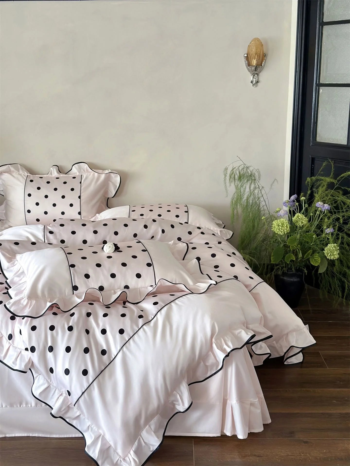 Angled shot of the Blush Pink & Black Polka Dot Ruffled Bedding Set in a well-lit room - RoomDen.