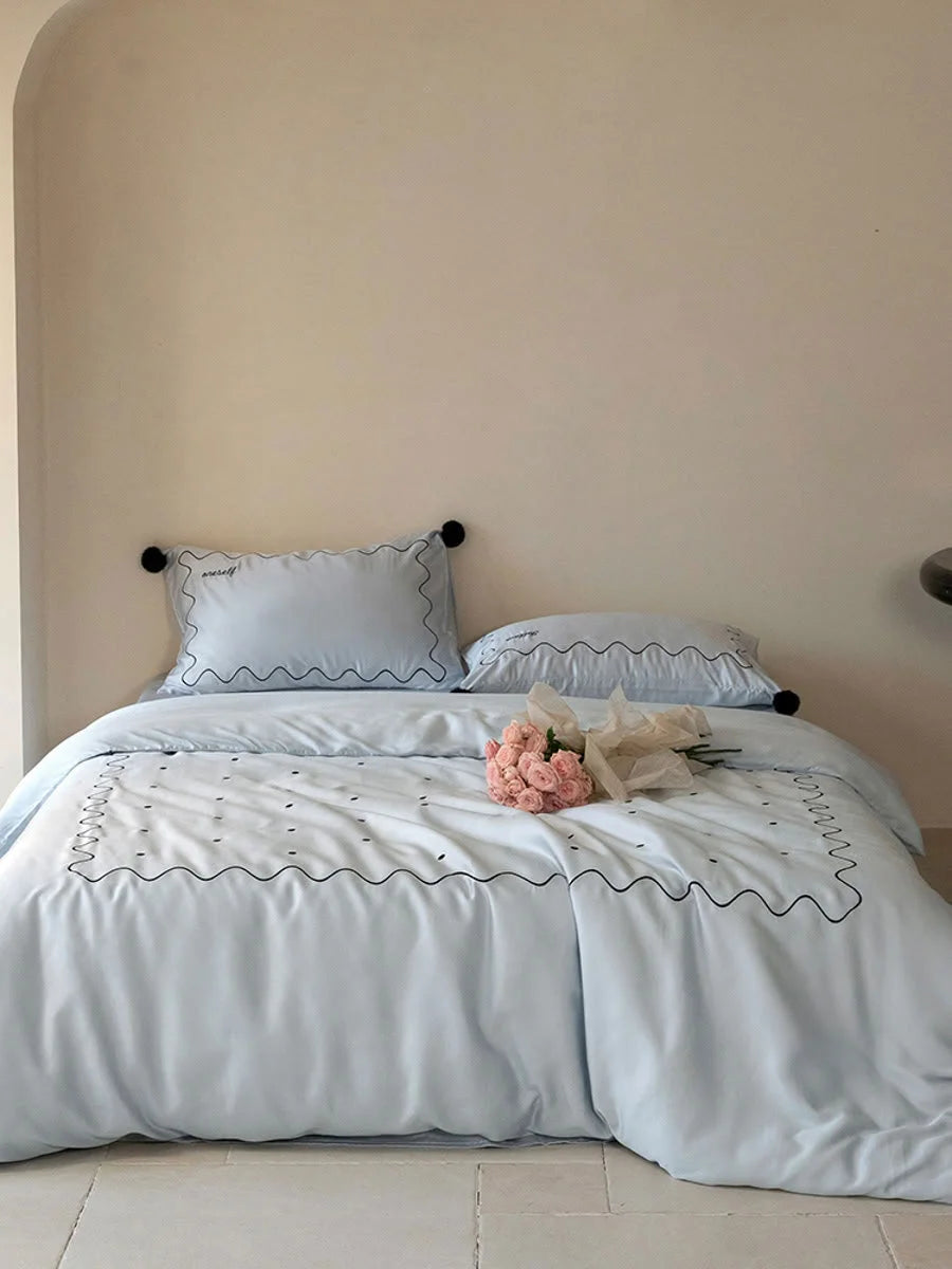 Full view of a bed made with the Baby Blue & Black pom pom Tencel bedding set, with pink roses on it. - RoomDen