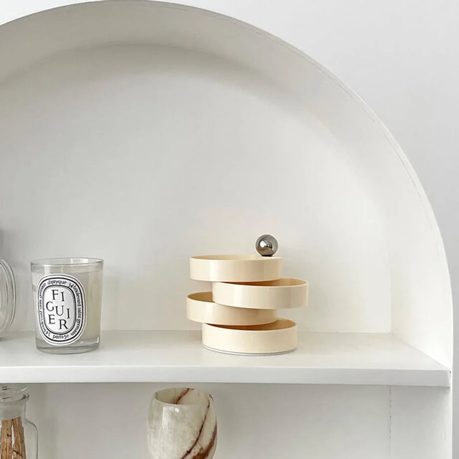 The Creamy Beige stacking jewelry organizer displayed on a white arched shelf next to a Diptyque candle. - RoomDen