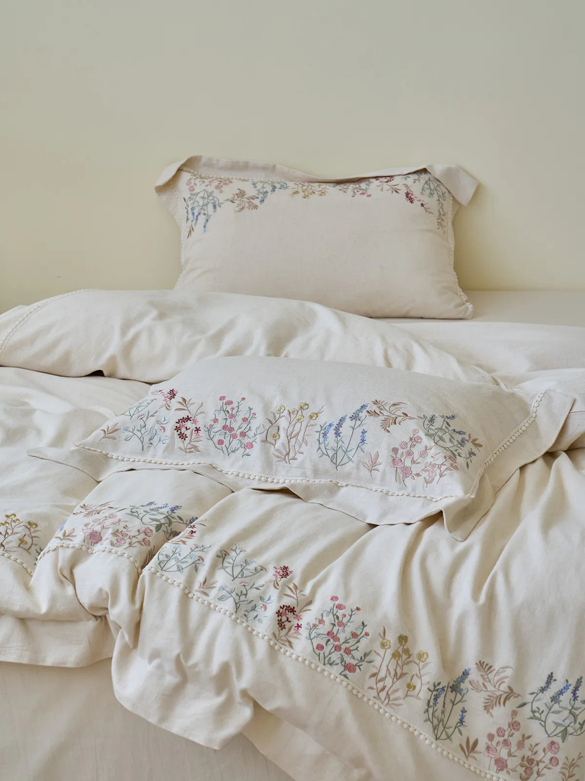 A cozy, styled bed featuring the Wildflower Embroidered Linen Duvet Cover and Pillowcases, creating a romantic, cottagecore vibe. - RoomDen