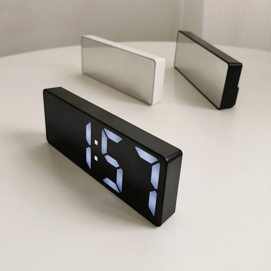 The black and white variants of the Sleek Mirrored Acrylic LED Table Clock on a neutral surface. - RoomDen