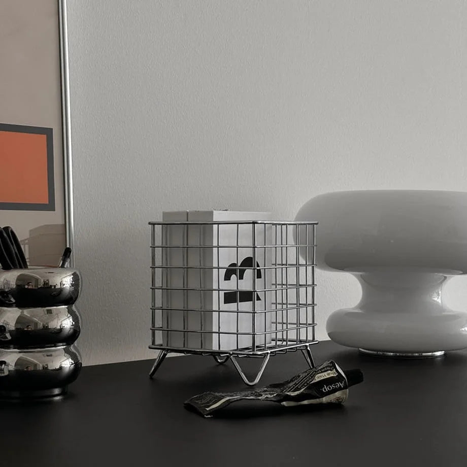 The chrome grid desktop caddy styled on a desk, capturing its sleek industrial design - RoomDen.