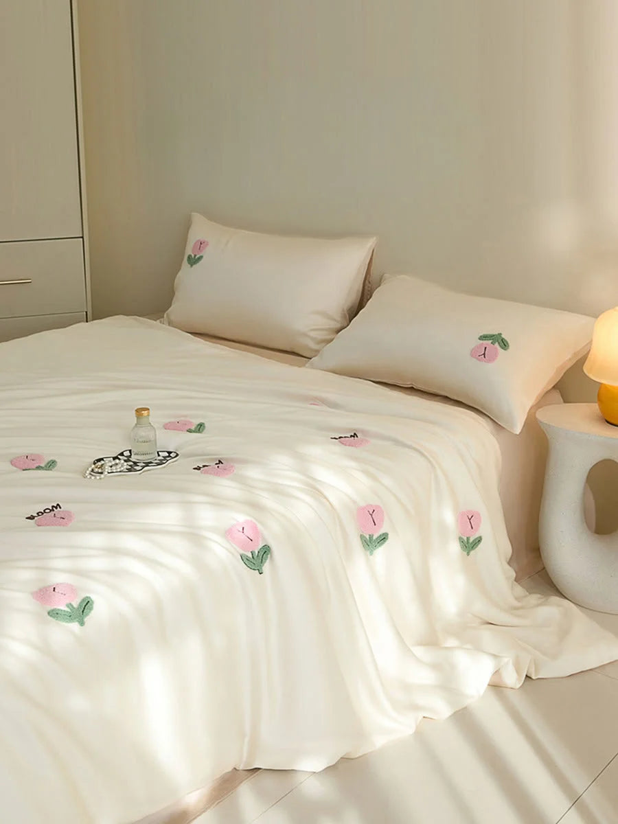 Angled shot of the Cream & Pink Tufted Doodle Flower bedding, showing the word 'BLOOM' embroidered. - RoomDen