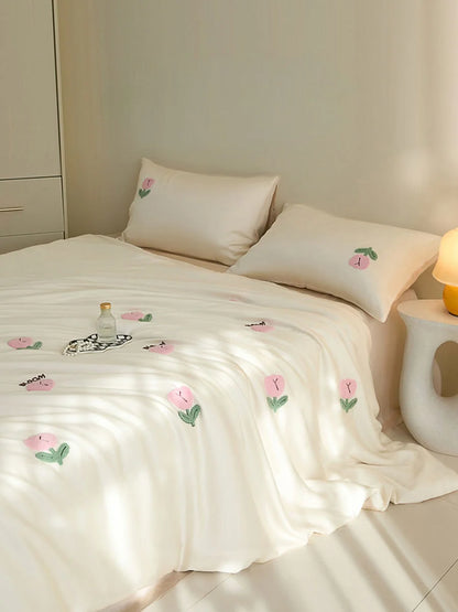 Angled shot of the Cream & Pink Tufted Doodle Flower bedding, showing the word 'BLOOM' embroidered. - RoomDen