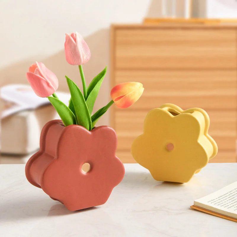Close-up of the Terracotta Red Daisy Bloom Ceramic Vase with pink tulips, sitting on a table with a book. - RoomDen