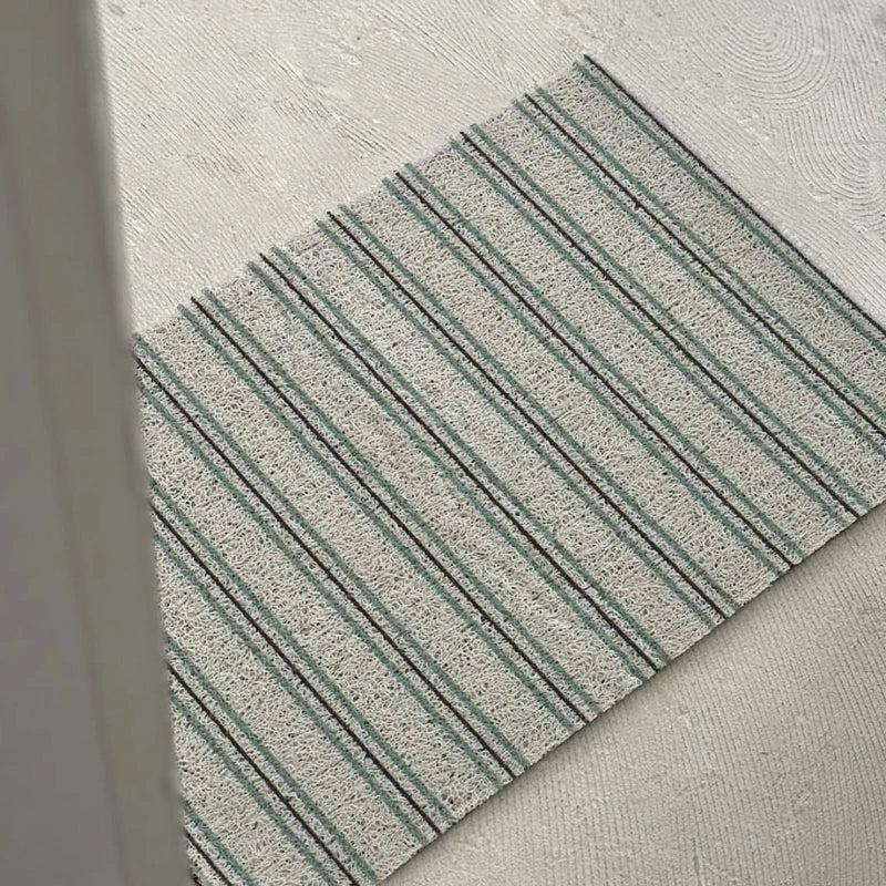 Angled view of a green striped loop-pile PVC coil rug on light flooring - RoomDen