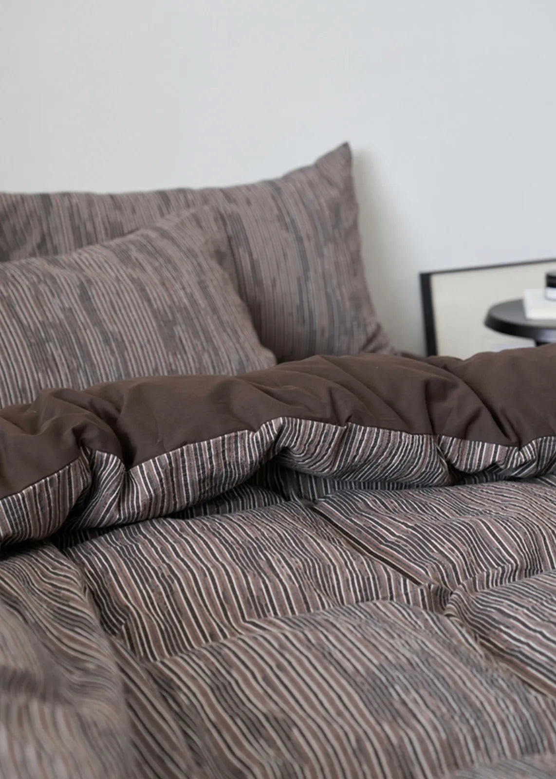 Detailed view of the corner of the Mocha Brown pinstripe duvet cover, showing its soft folds.