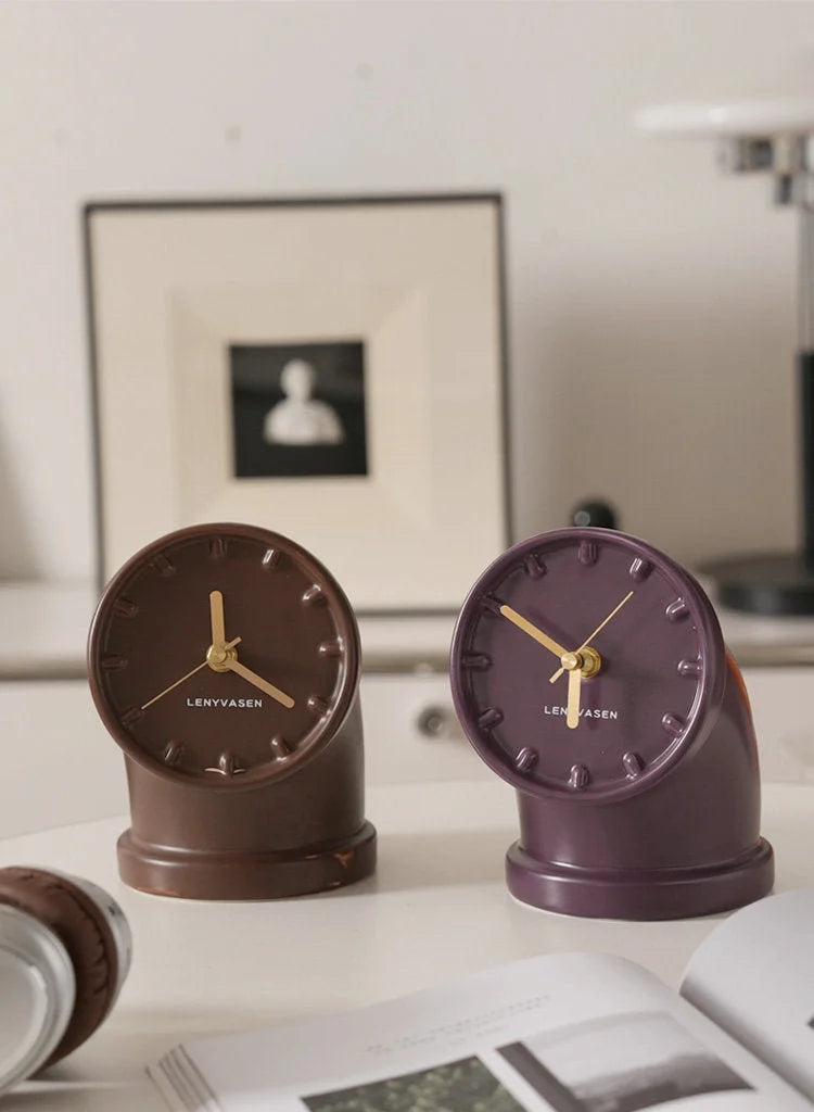 Mocha brown and plum purple Industrial Pipe Ceramic Table Clocks displayed on a white desk with framed art in the background - RoomDen
