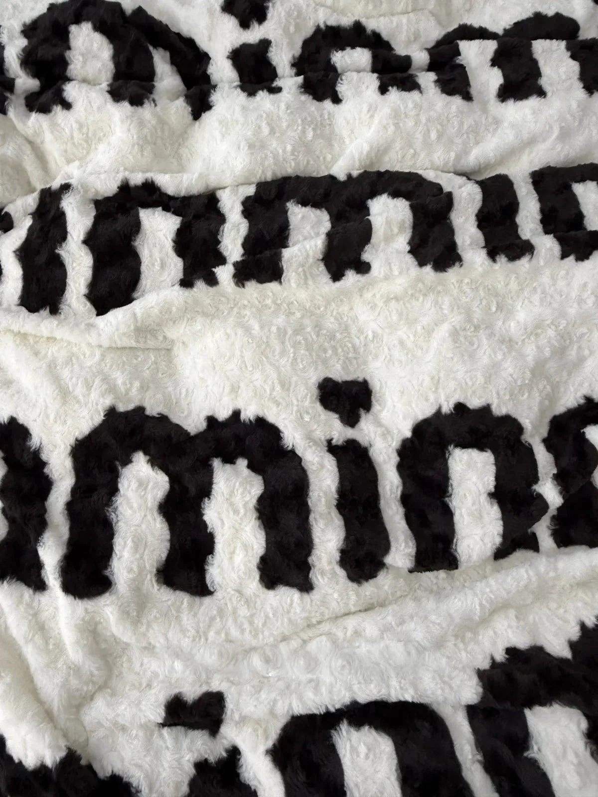 Close-up detail shot of the fuzzy texture on the white flannel fleece with black lettering. - RoomDen