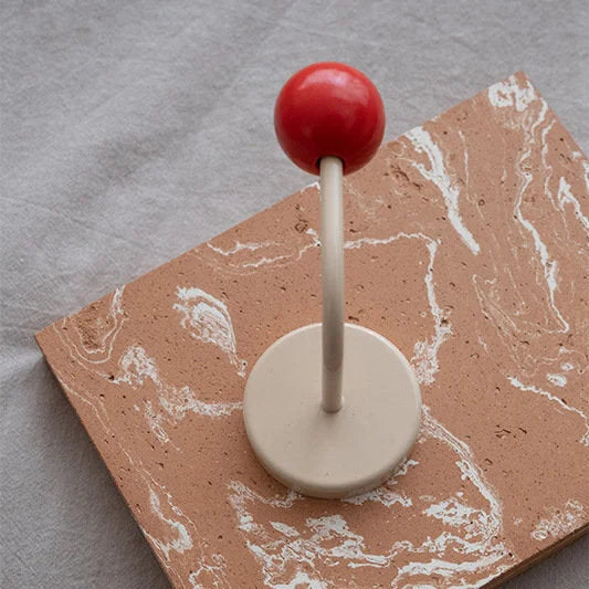 The Red & Beige Color Block Metal Hook displayed on a marbled terracotta tile - RoomDen.