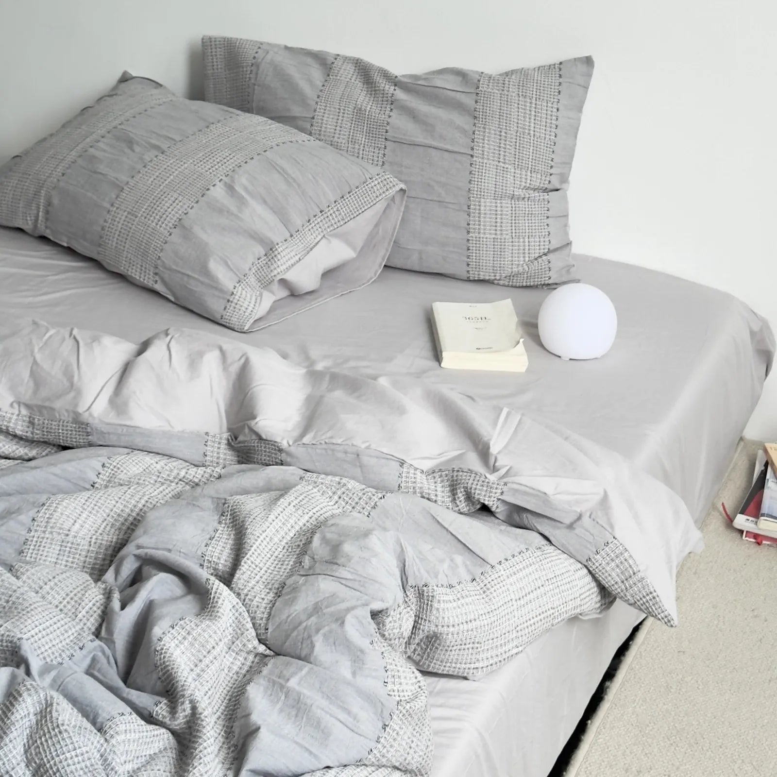 Cloud Grey variant of the textured woven stripe bedding set on a bed in a minimalist white room.