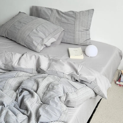 Cloud Grey variant of the textured woven stripe bedding set on a bed in a minimalist white room.