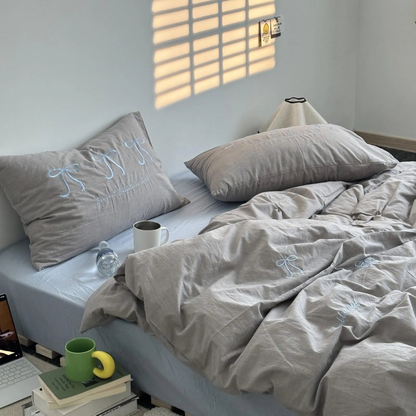 A beige washed cotton bedding set with light blue embroidered bows, styled on a bed for a soft, neutral look. - RoomDen