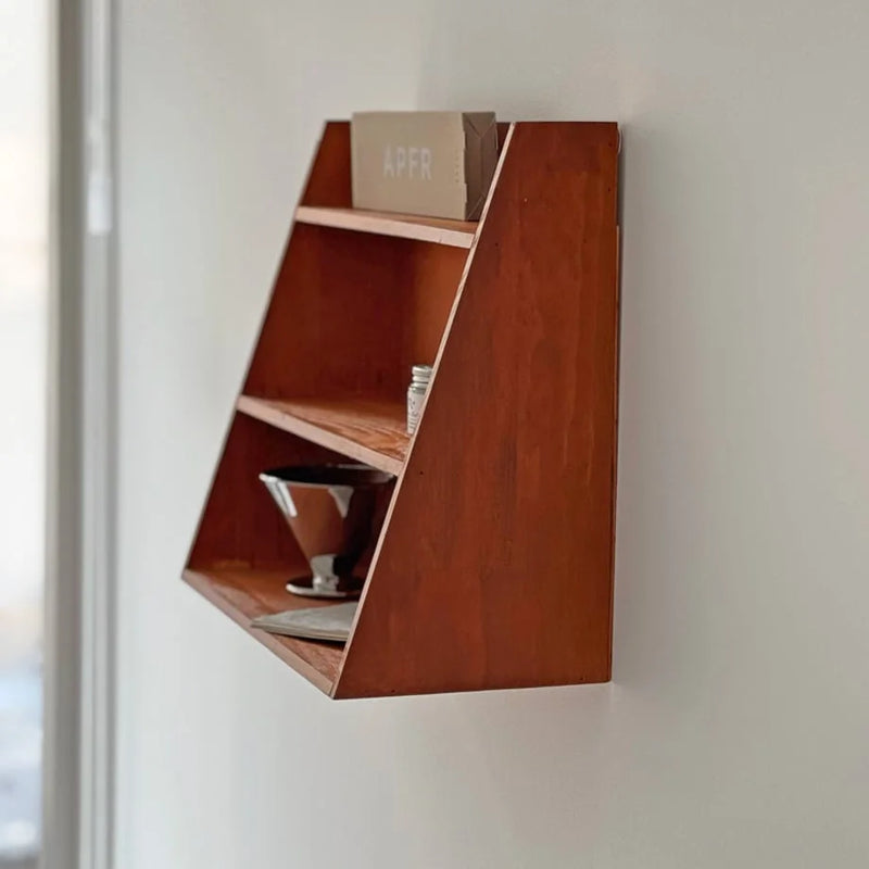 Side profile of a slanted natural-grain wood wall shelf against a quiet bare wall - RoomDen