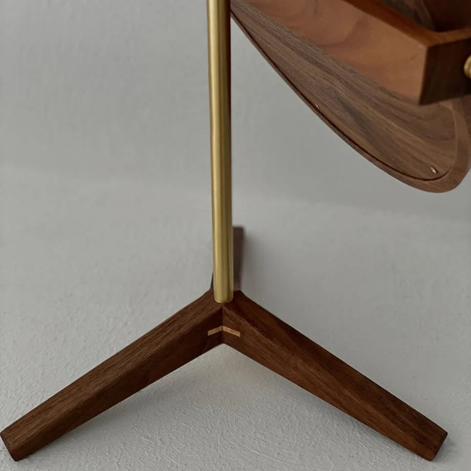 Detailed shot of the tripod base of the walnut mirror, showing the expert joinery and brass stem.