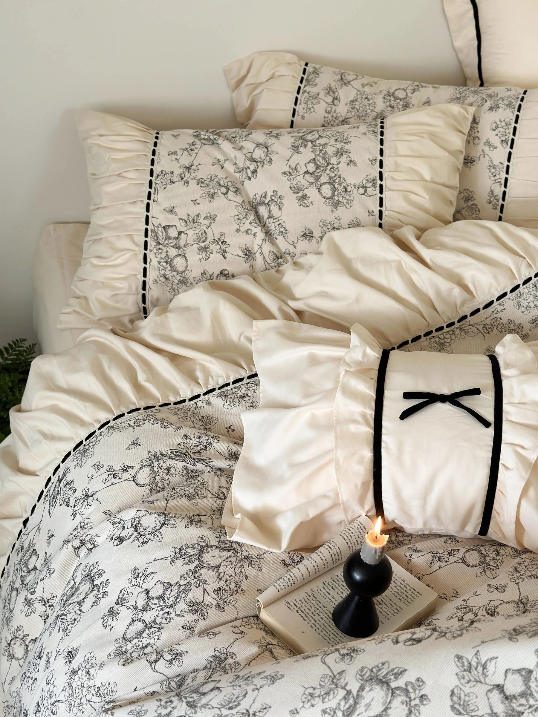Overhead shot of the Cream Toile bedding with a lit candle and open book, focusing on the vintage floral print. - RoomDen