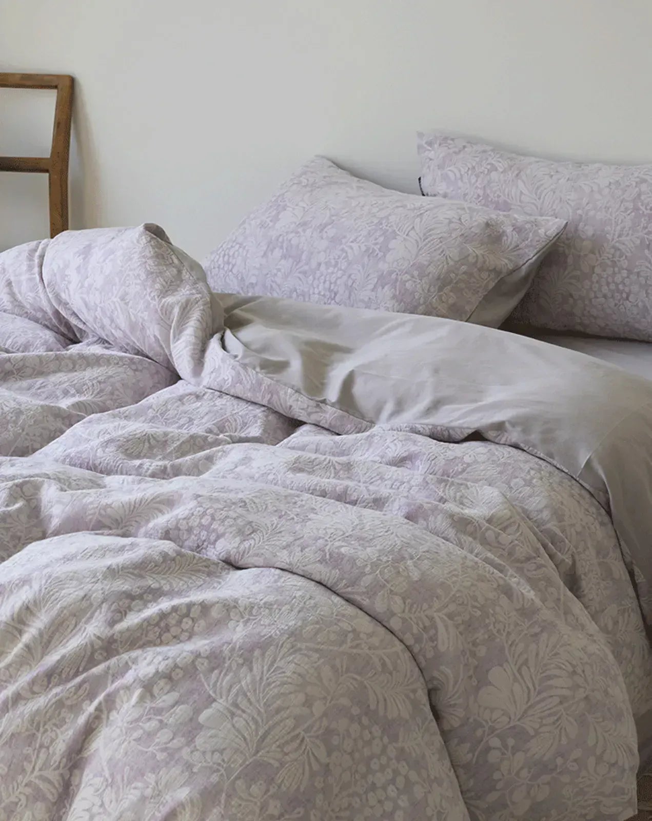 The Jacquard Botanical Washed Cotton Bedding Set in a dusty lavender color, showing the rumpled texture and reversible grey side - RoomDen.