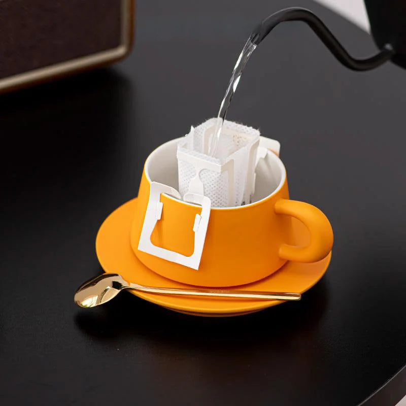Pouring hot water into a Marigold Orange ceramic coffee cup with a drip coffee bag, set on a black desk. - RoomDen