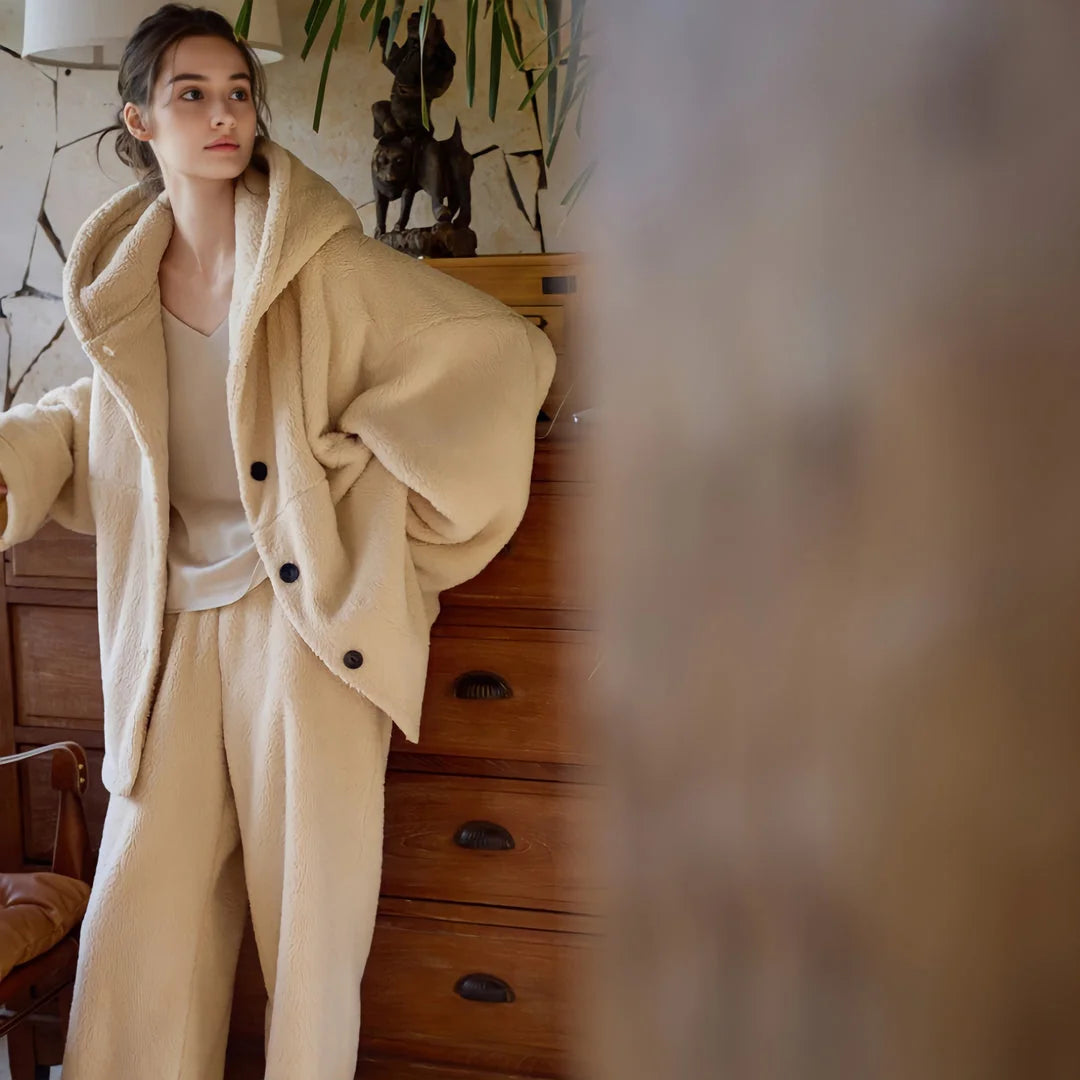 Model standing by a wooden dresser in a full beige flannel fleece pajama outfit. - RoomDen