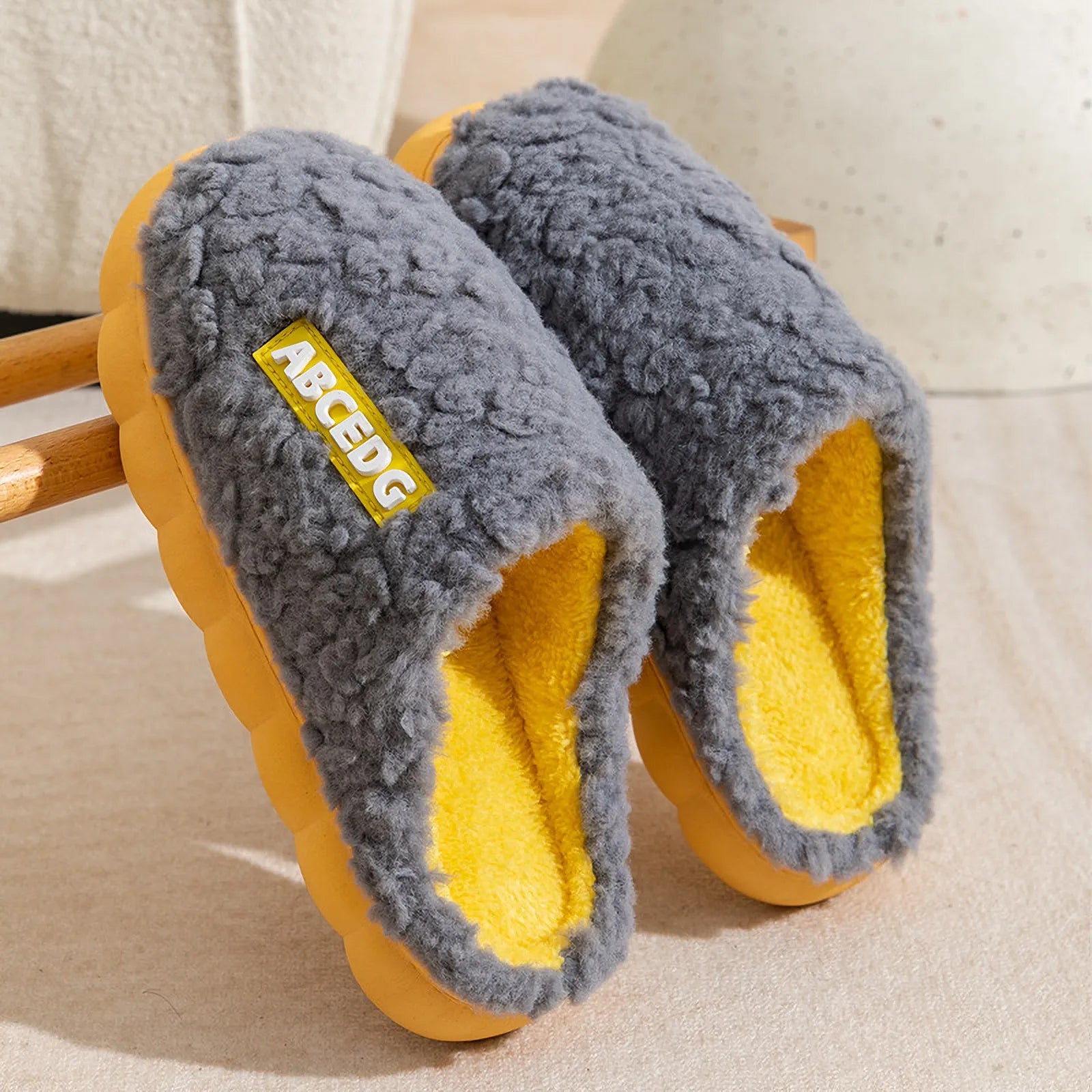 Grey upper with yellow sole plush house slippers hanging on wooden rack - RoomDen