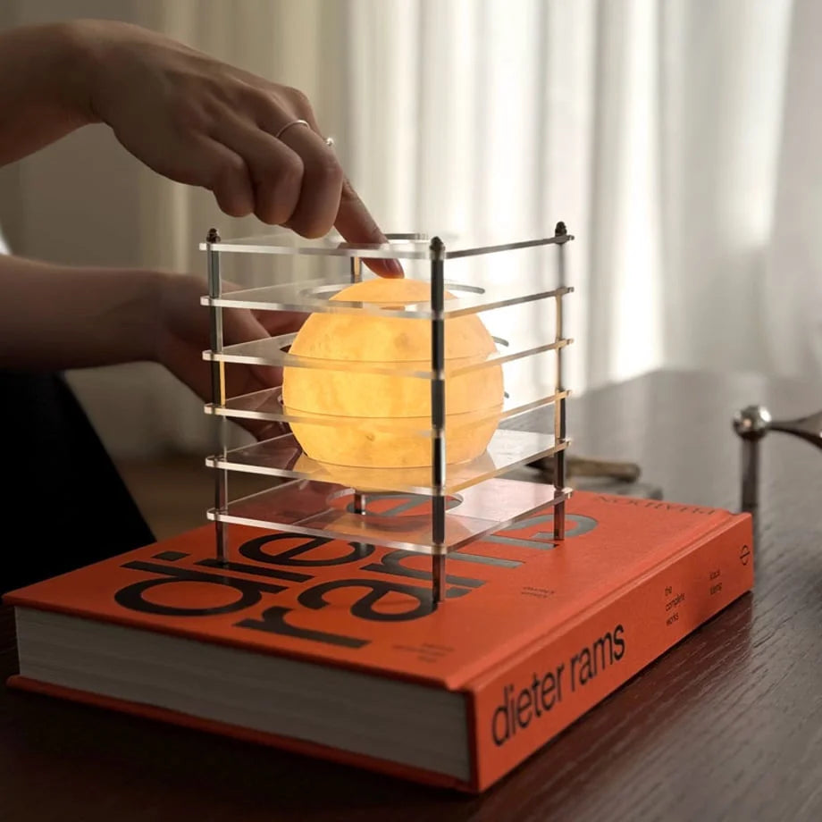 A hand touching the top of the Crystal Clear Caged Moon Lamp to demonstrate the touch-dimming feature - RoomDen