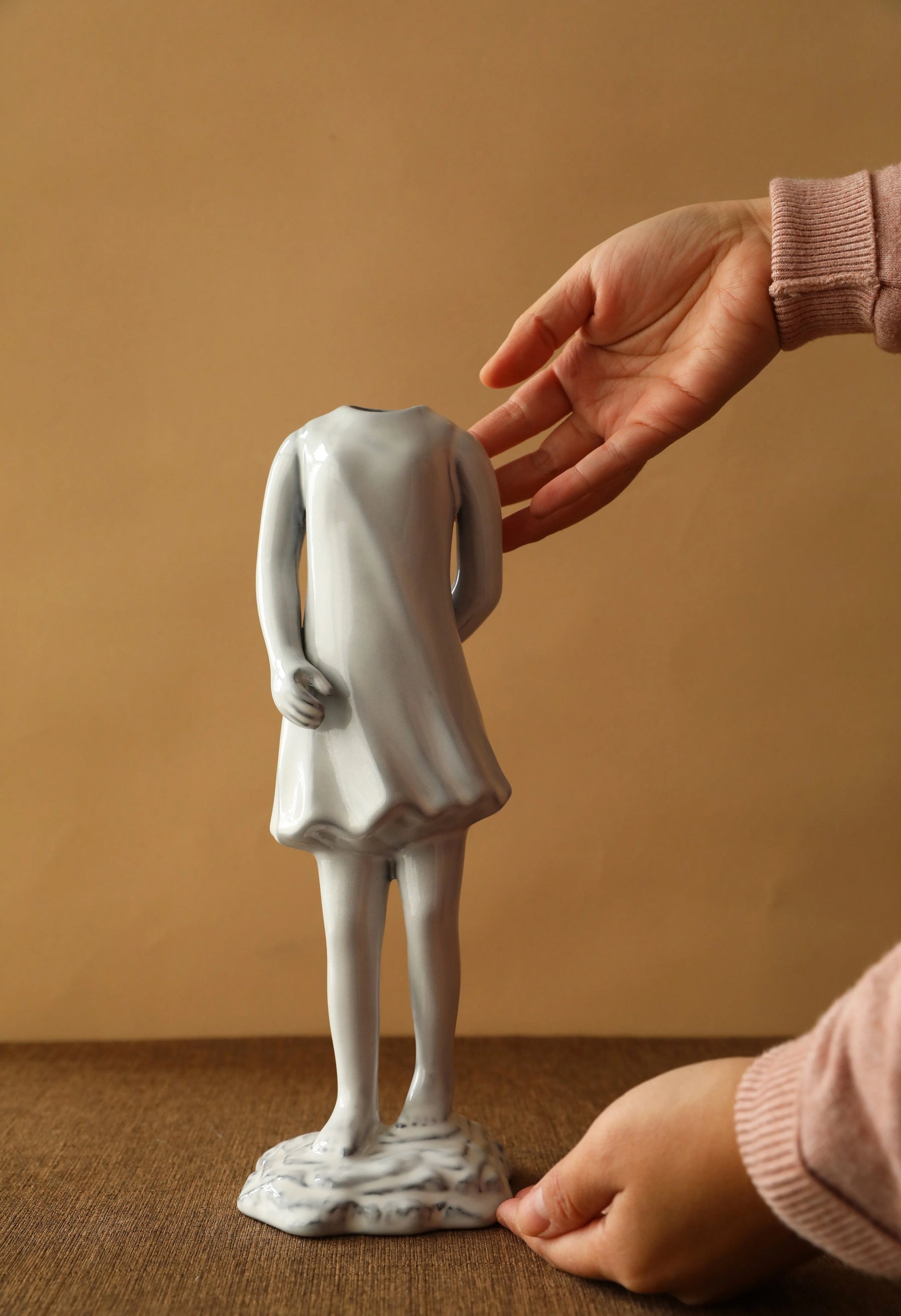 Hand presenting the ceramic vase shaped like a girl in a dress from behind. - RoomDen