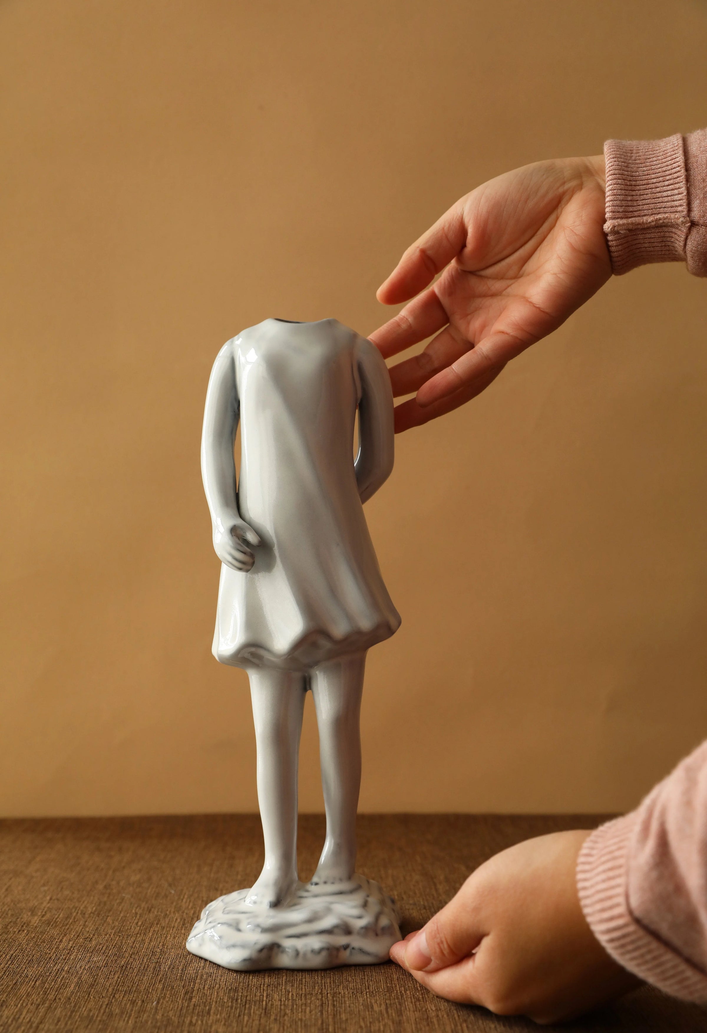 Hand presenting the ceramic vase shaped like a girl in a dress from behind. - RoomDen