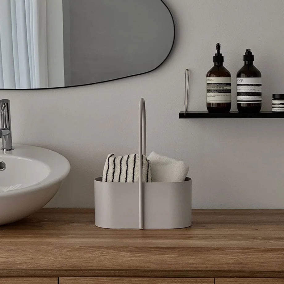 The beige metal organizer caddy on a bathroom vanity, holding towels next to a sink. - RoomDen