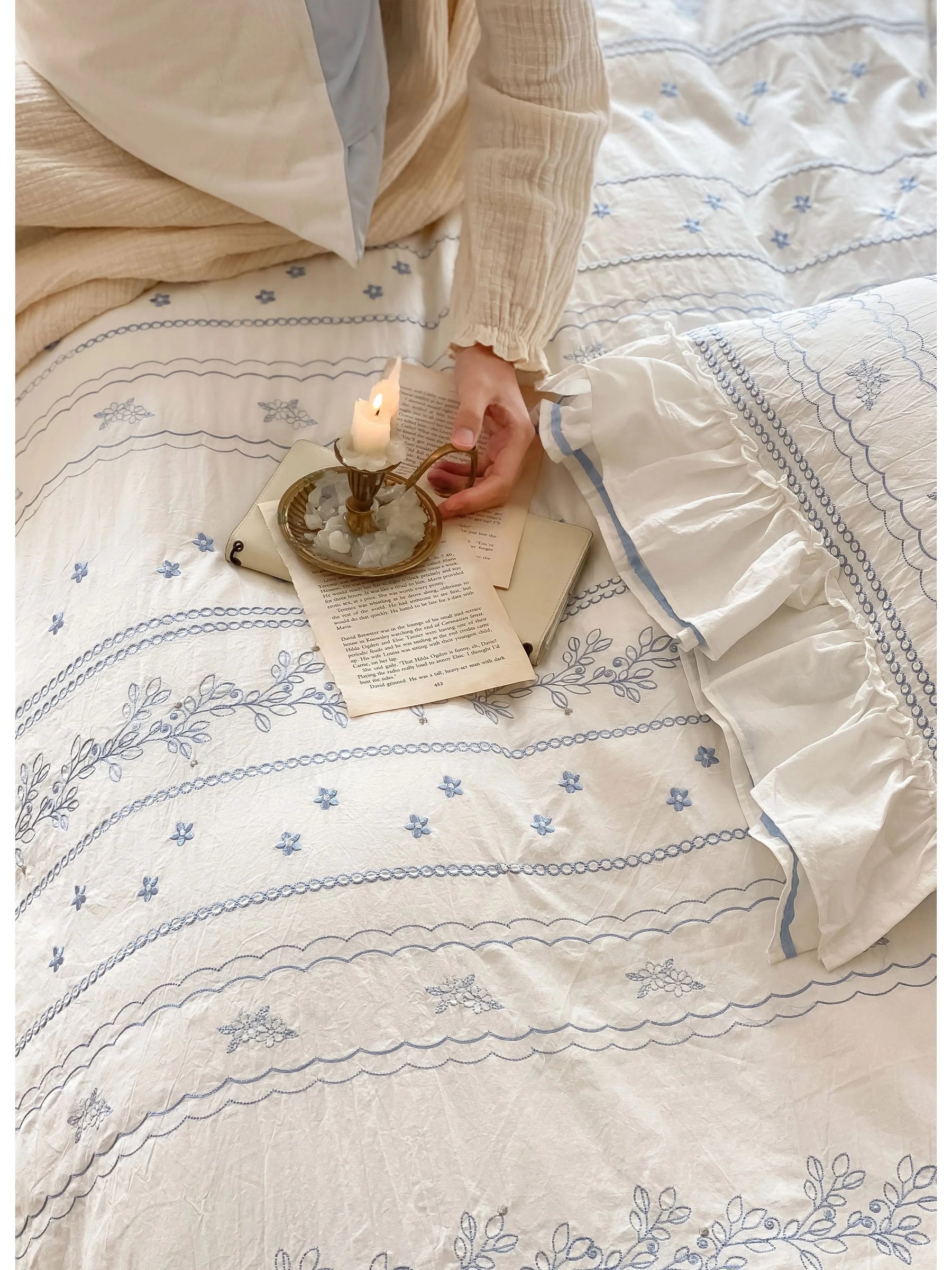 A hand holding a candle over the Ruffled Floral Vine Embroidered Duvet Cover, highlighting the texture.
