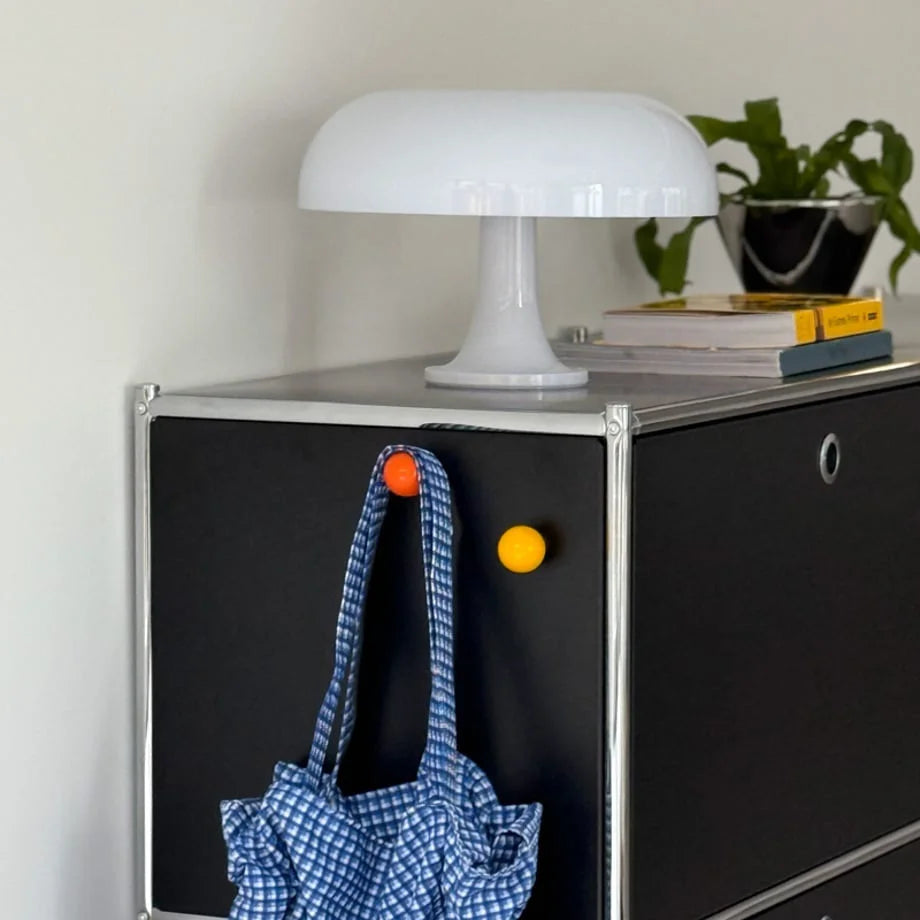 Orange and yellow magnetic hooks on a black metal cabinet holding a blue gingham bag. - RoomDen