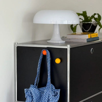 Orange and yellow magnetic hooks on a black metal cabinet holding a blue gingham bag. - RoomDen