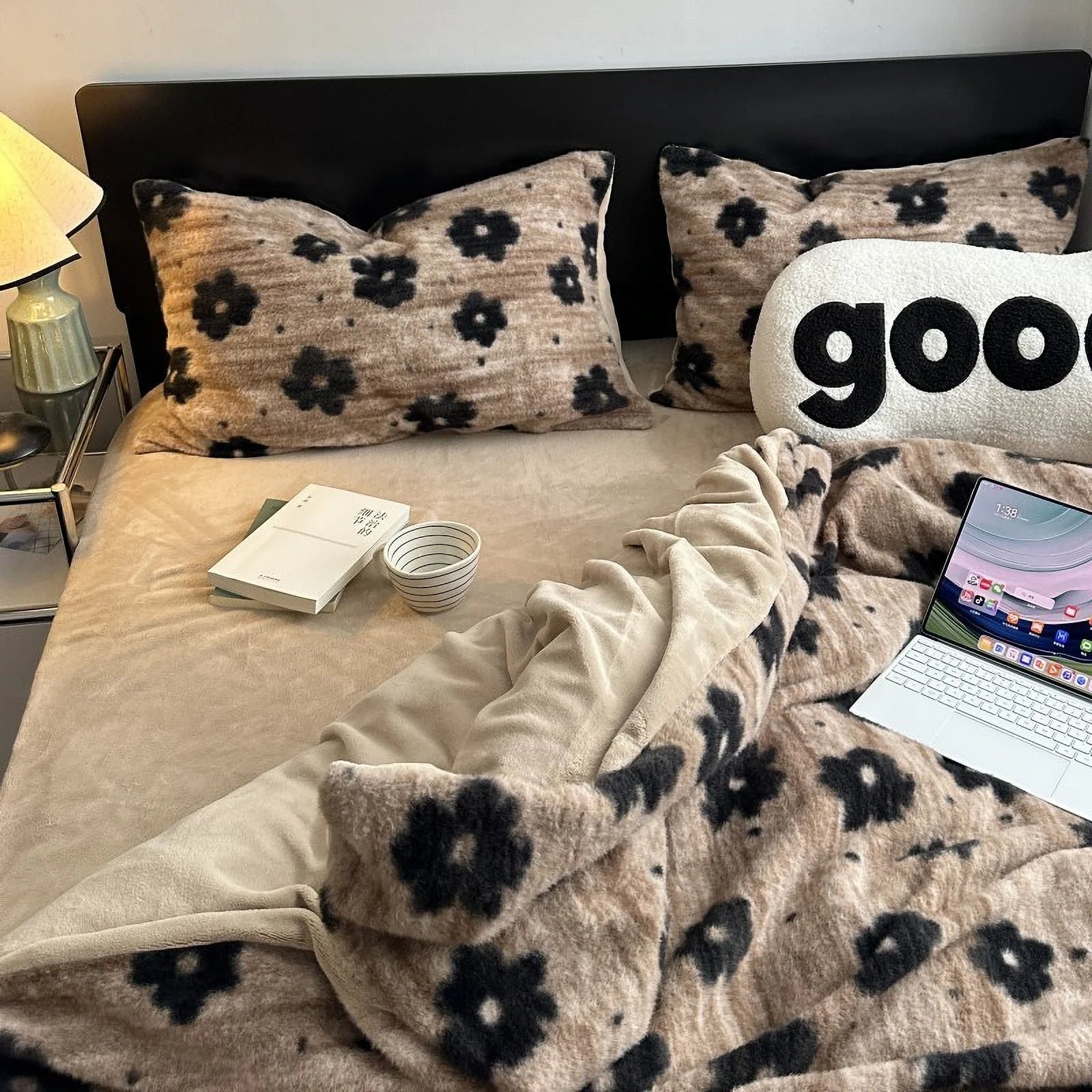 A full view of a bed styled with the plush retro floral flannel fleece bedding set, with a laptop and book, creating a cozy, lived-in scene. - RoomDen
