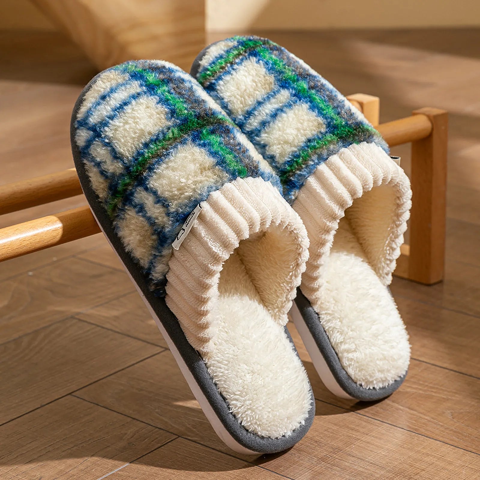 Green and blue plaid sherpa slippers leaning against a wooden rack showing tartan pattern - RoomDen