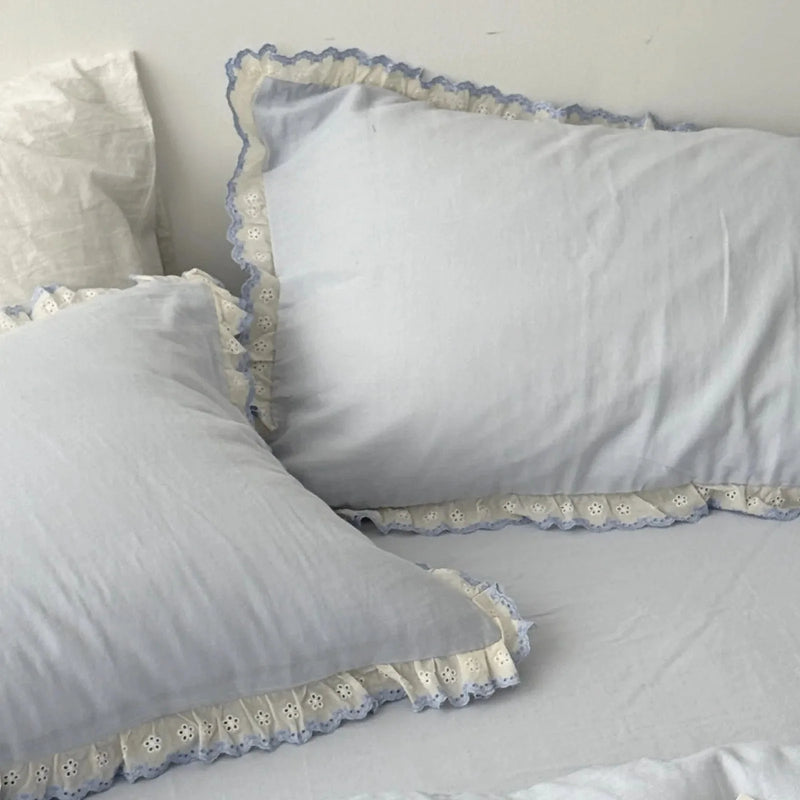 Close-up of two sky blue pillowcases with white and blue embroidered lace ruffle trim — RoomDen
