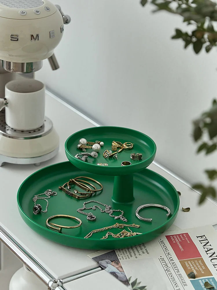 Emerald green two-tier organizer tray holding jewelry on a white desk next to a coffee machine. - RoomDen