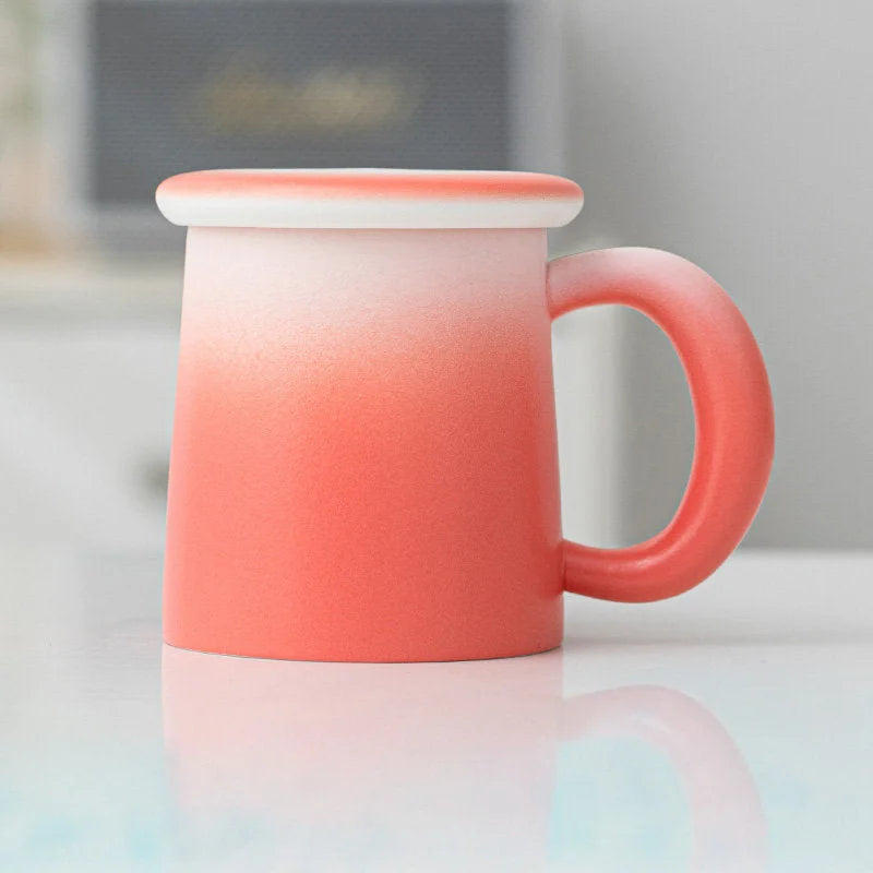 Angled view of the Coral Ombre Frosted Ceramic Mug with lid - RoomDen.