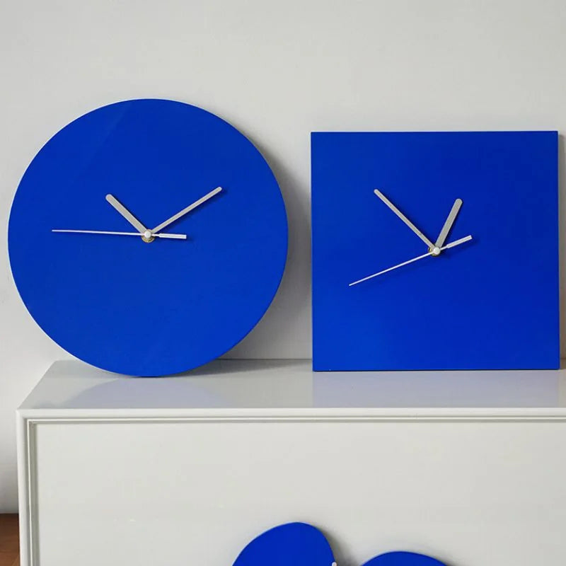 The round Klein blue wall clock placed next to a square version on a white console table, showcasing its geometric simplicity - RoomDen.