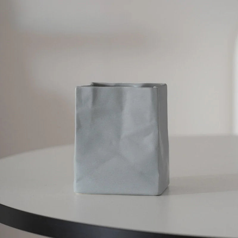 A single ash grey crumpled ceramic organizer on a white table with soft lighting. - RoomDen