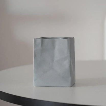 A single ash grey crumpled ceramic organizer on a white table with soft lighting. - RoomDen