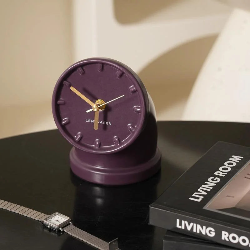 Close-up of the plum purple Industrial Pipe Ceramic Table Clock on a black side table next to a watch - RoomDen