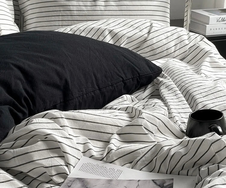 Detailed close-up shot of the crinkled texture of the pinstripe duvet cover next to a black mug. - RoomDen