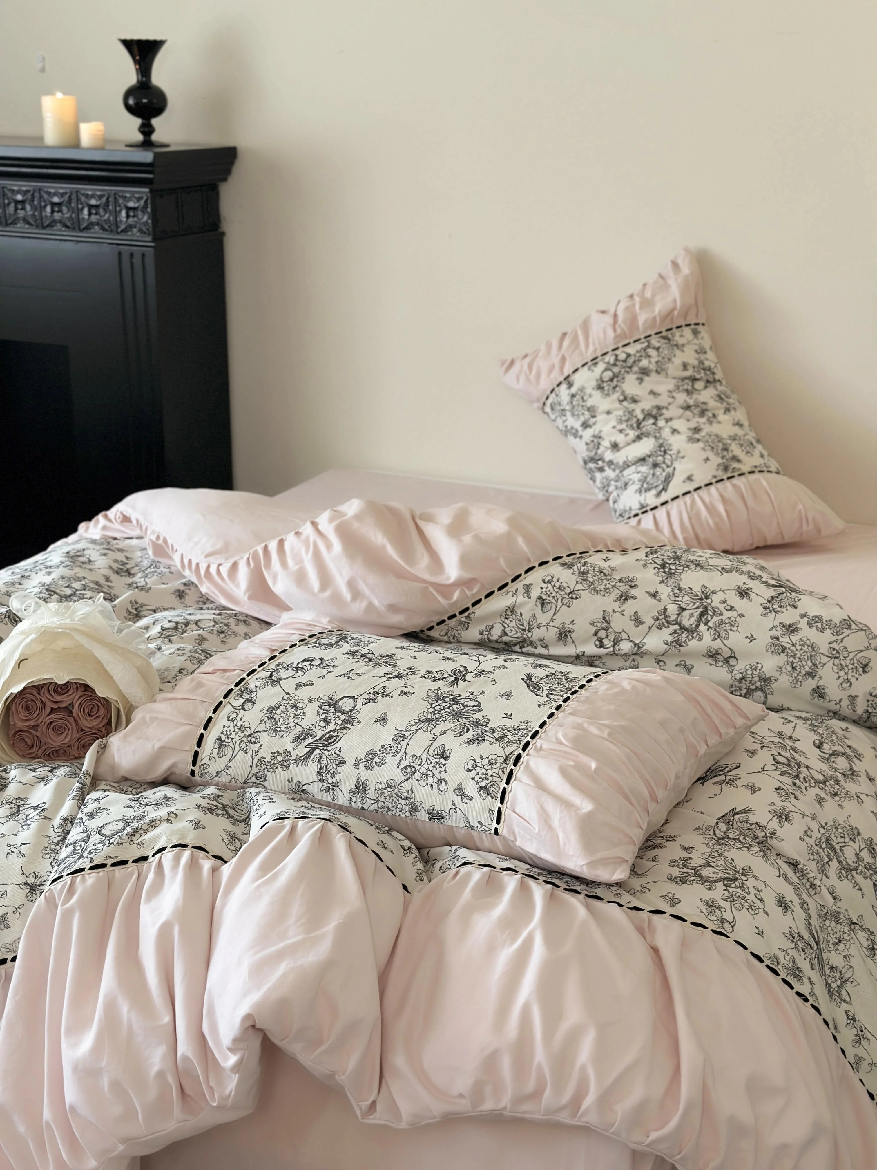 Side view of the bed with the Pink Toile bedding set near a black fireplace. - RoomDen