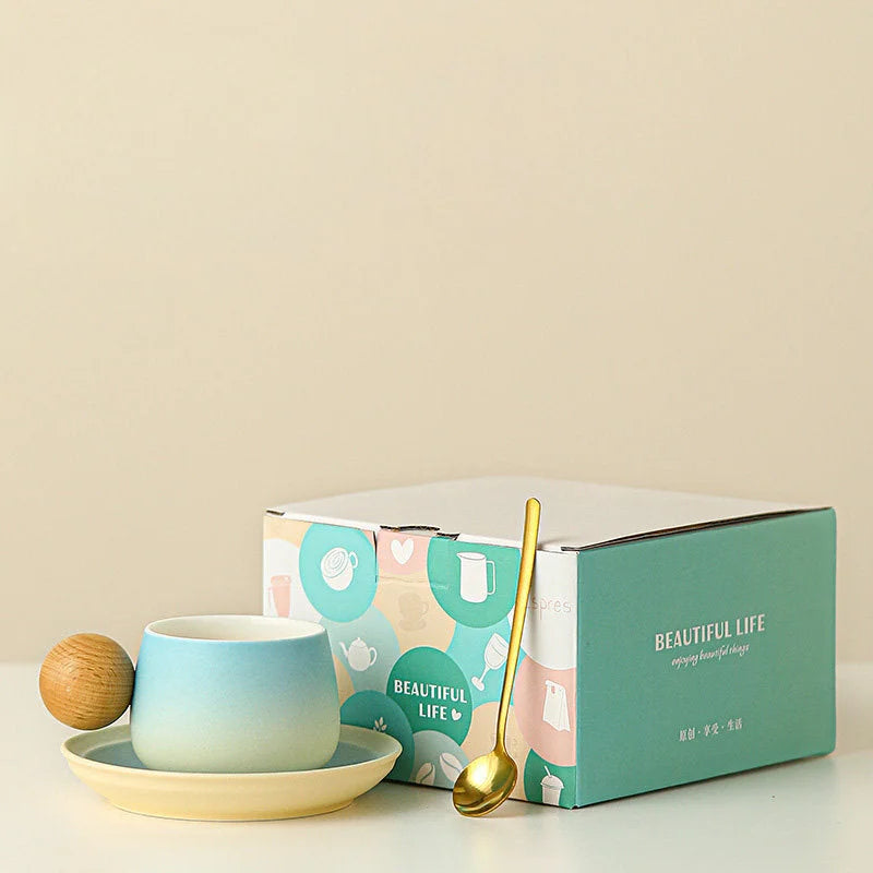 The Sky Blue gradient ceramic mug and saucer set with a golden spoon, shown next to its stylish gift box. - RoomDen
