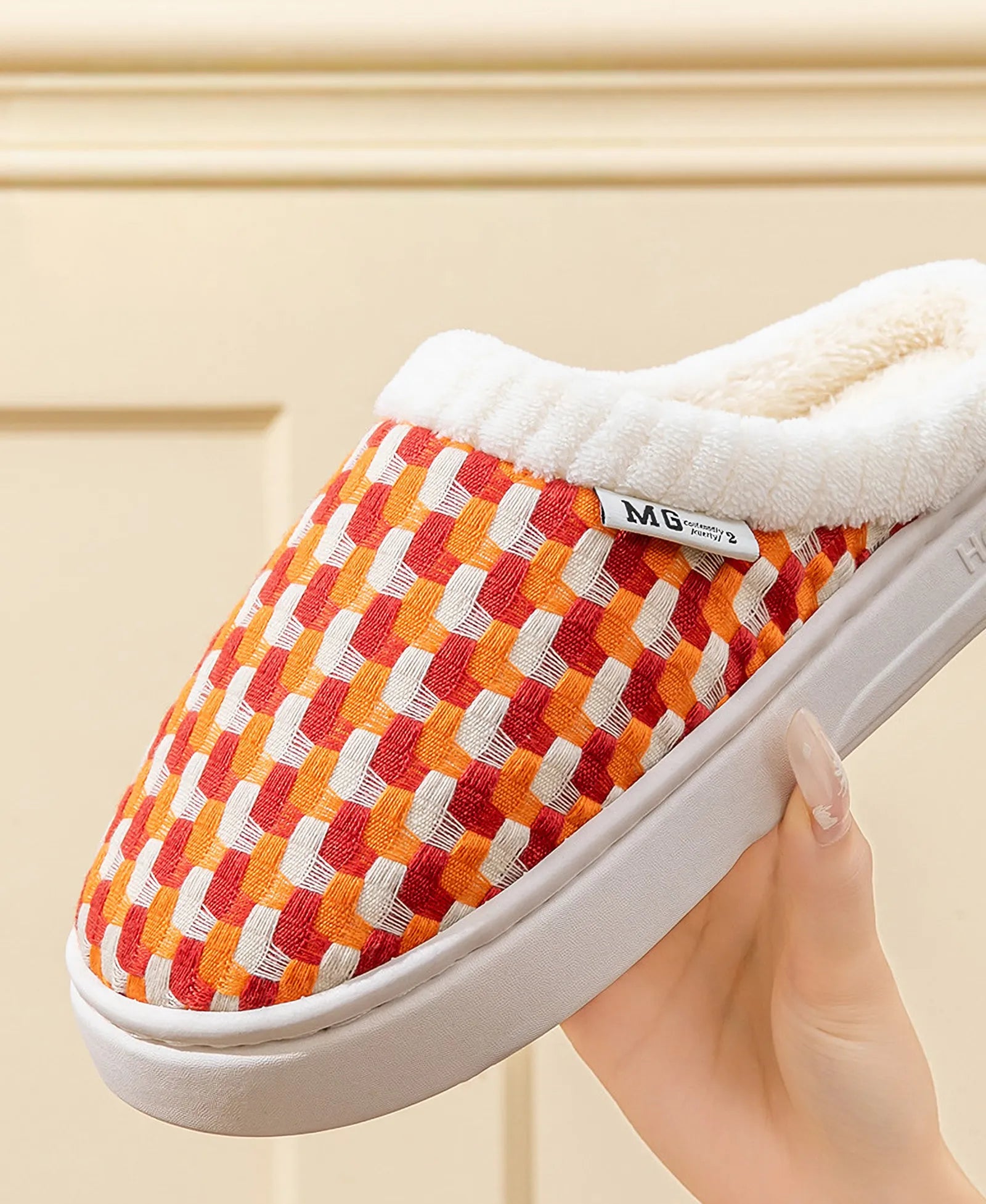 Hand holding orange woven plush slipper showing soft texture and thick sole - RoomDen