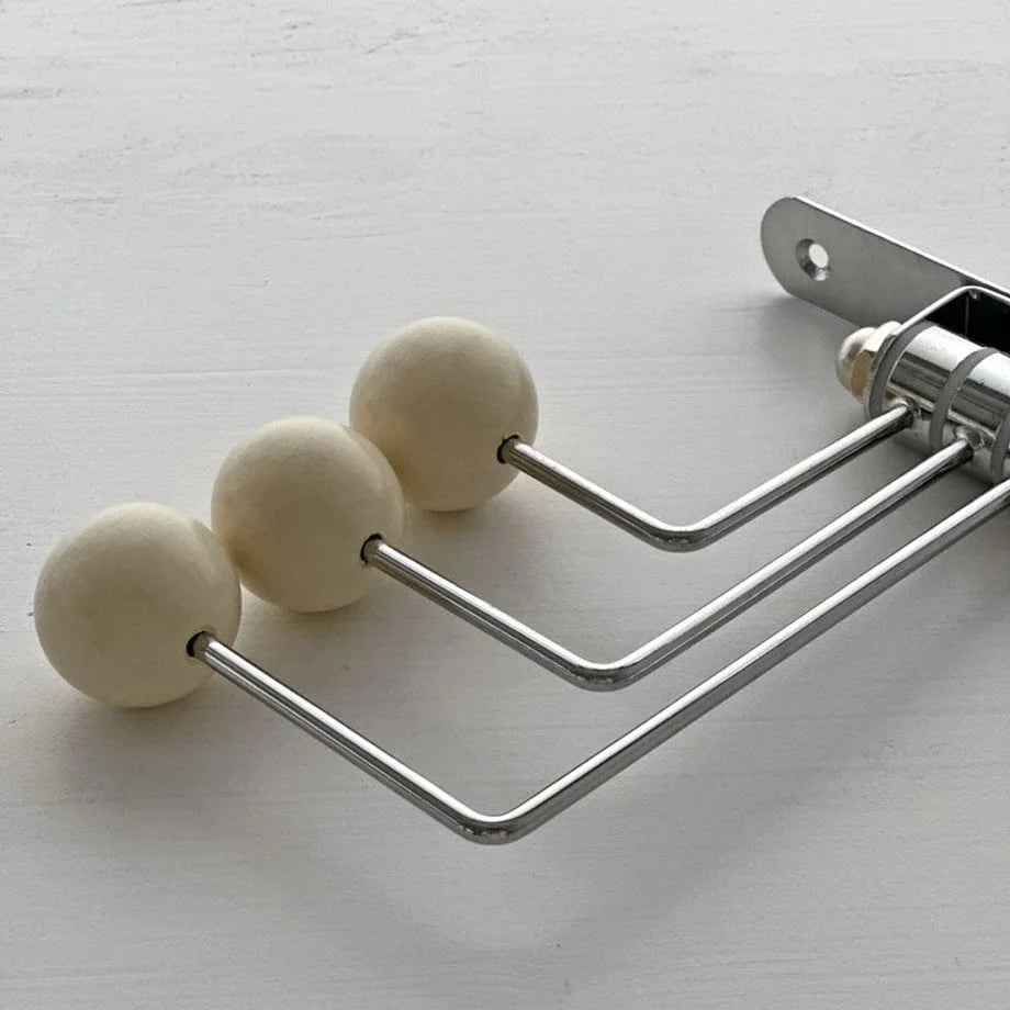 Macro detail shot of the three smooth cream spheres and metal arms of the wall hook - RoomDen.